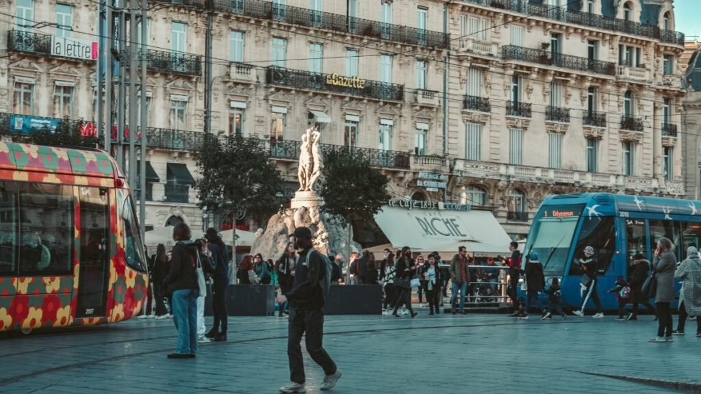 Passants et tramways sur la place de la Comédie, au cœur du centre-ville commerçant de Montpellier (Hérault)